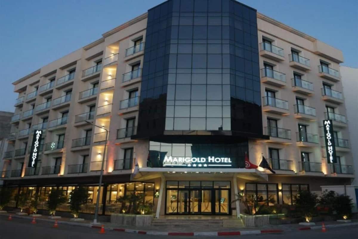 A multi-story hotel with a prominent glass facade, a central entrance, and a flag.