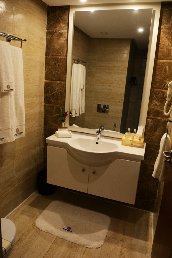 Un baño con un espejo grande, un lavamanos y un inodoro.