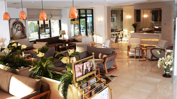 A spacious living room with multiple seating areas, a coffee table, and a dining area with a kitchen in the background. - Marigold Hotel (Tunis)