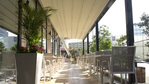 An outdoor seating area with white chairs and a large planter with flowers. - Marigold Hotel (Tunis)