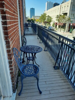 A wooden deck with metal railings, a table, and a chair.