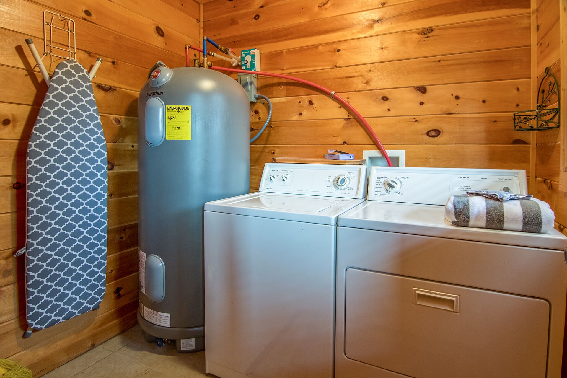 A laundry room with a large water heater, a washing machine, and a dryer.