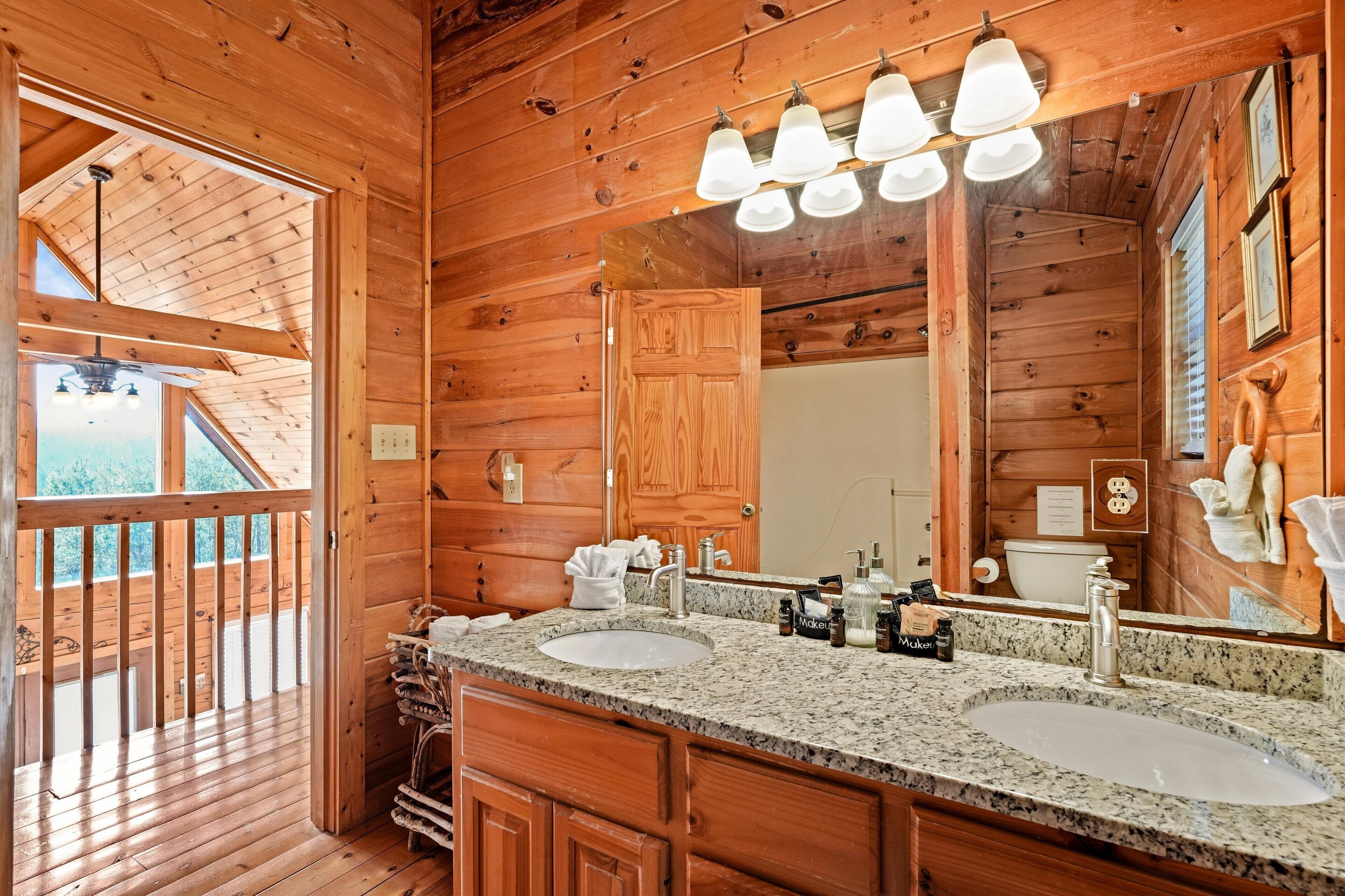 A wooden cabin bathroom with two sinks, a large mirror, and a wooden ceiling.