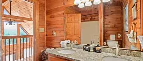 A wooden cabin bathroom with two sinks, a large mirror, and a wooden ceiling.