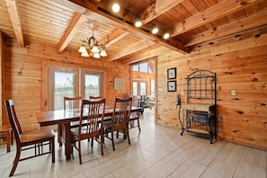 A wooden interior with a dining table, chairs, and a bench.