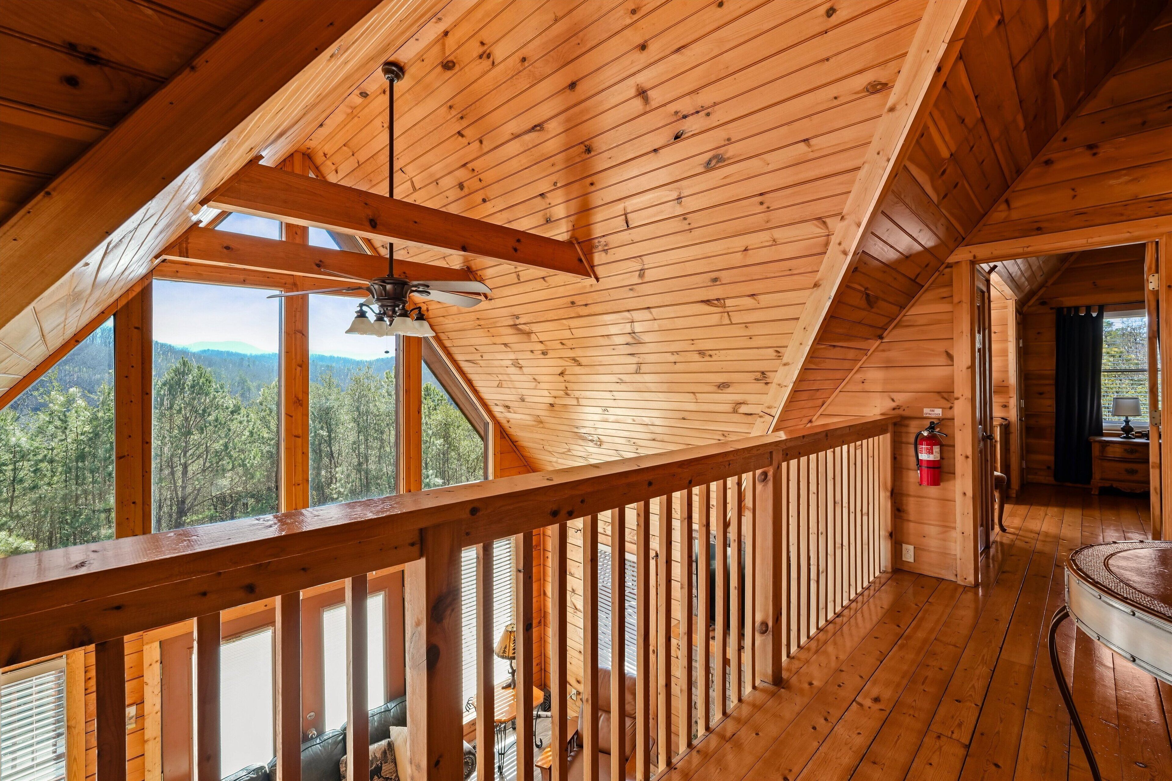 A wooden cabin with a balcony, a ceiling fan, and a fire extinguisher.