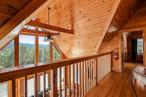A wooden cabin with a balcony, a ceiling fan, and a fire extinguisher.