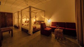 Una habitación con una cama con dosel, un sofá, un banco de madera y una pequeña mesa.