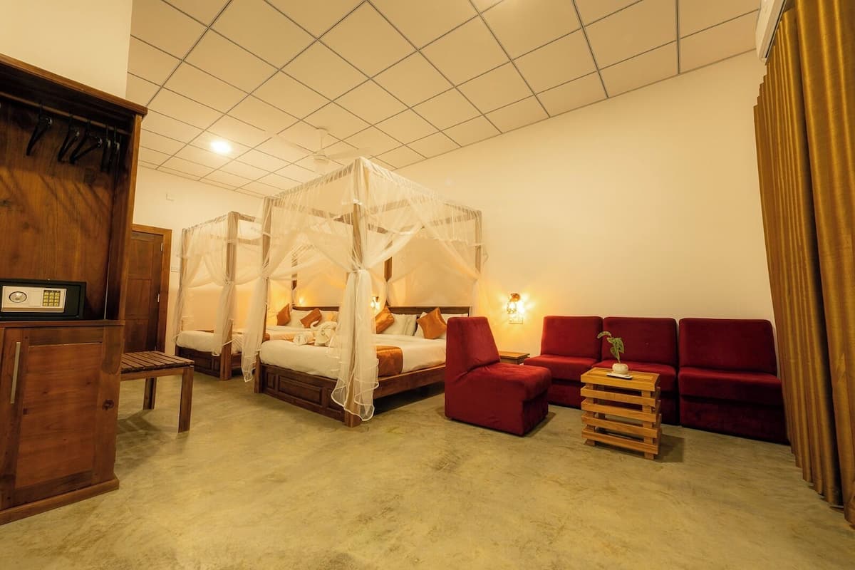 A bedroom with a four-poster bed, a wooden cabinet, a red sofa, and a bedside table with a lamp.