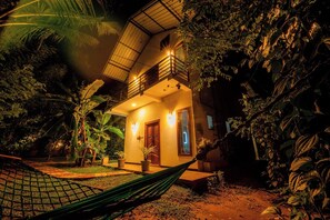 A house with a balcony, surrounded by lush vegetation.