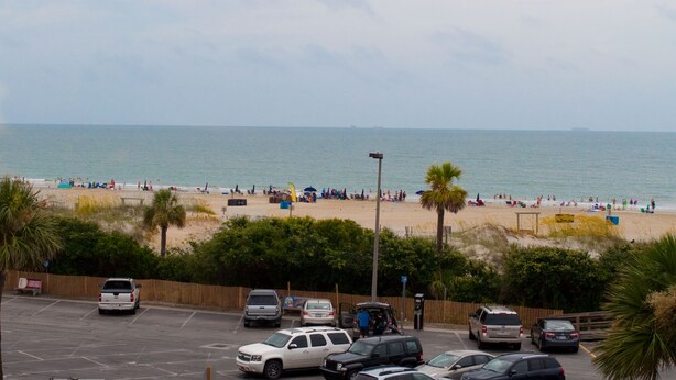 A beach with parked cars and people enjoying the shore. - Brass Rail 3 Bed, 2.5 Bath Ocean View Top Floor Closest To Beach (Tybee Island)