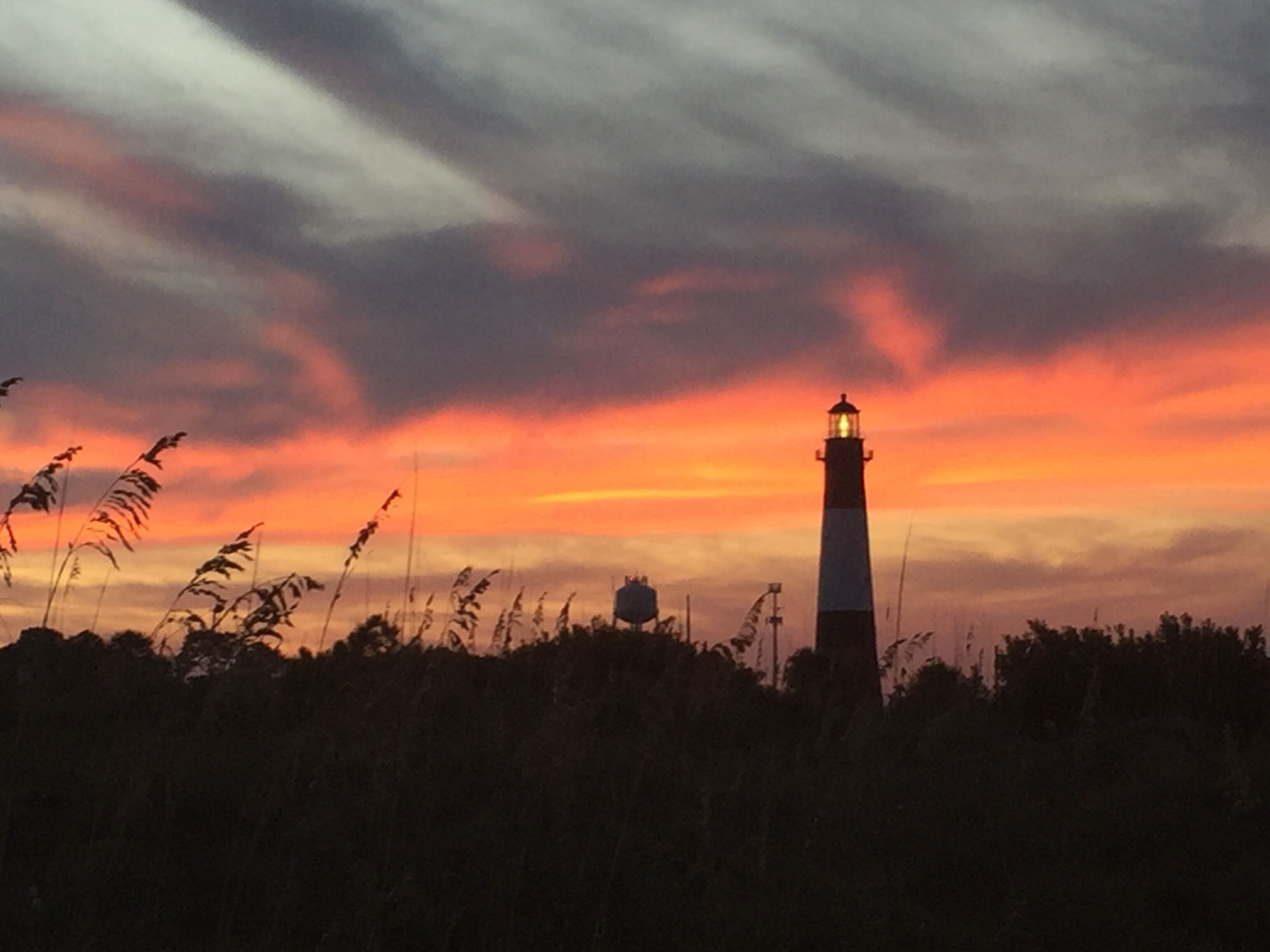 A lighthouse silhouette against a sunset sky.