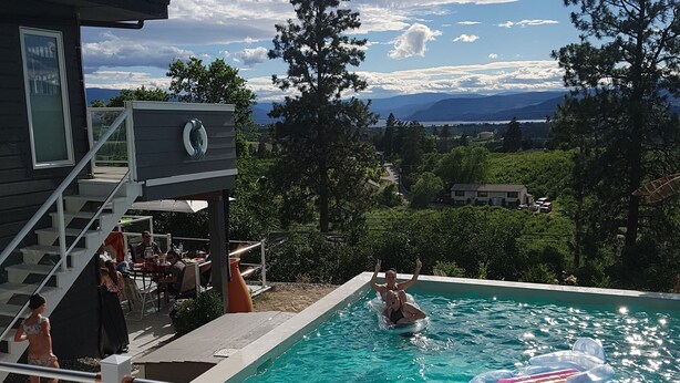 Una piscina con agua cristalina, rodeada de árboles y con vistas a montañas distantes.