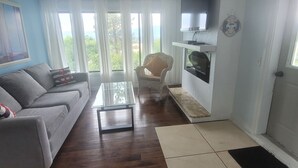 Una sala de estar con sofá, una mesa de centro, una silla, televisor y chimenea.