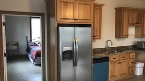 Una cocina con armarios de madera, un refrigerador de acero inoxidable, lavavajillas y encimera de granito.