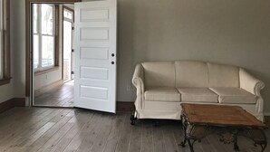 Una habitación con una puerta blanca, un sofá color beige y una mesa de centro de madera.
