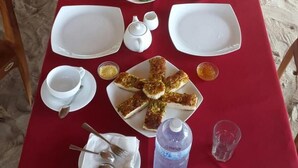 A table set for a meal with plates, cutlery, a water bottle, and a vase with flowers. - Reef Pasikudah (Nasuvantivu)