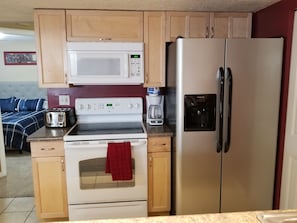 A compact kitchen with a microwave, stove, and refrigerator. - Your Clearfield home (Clearfield)