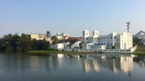 Un edificio blanco grande con una cúpula y dos torres, ubicado junto a una masa de agua tranquila.