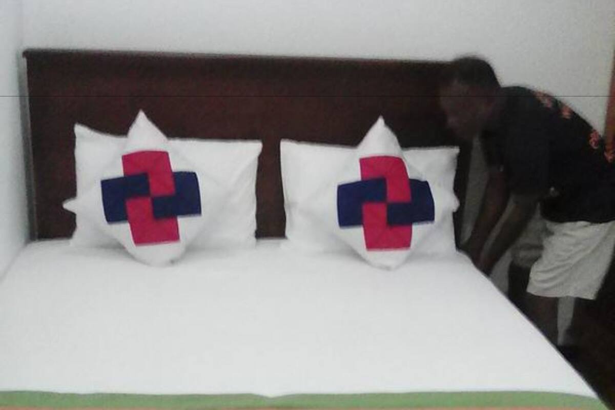 A bed with a striped bedspread and two pillows with a geometric design.