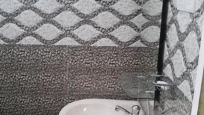 Un baño con un lavamanos pedestal blanco, un bote de basura verde y paredes con diseño.