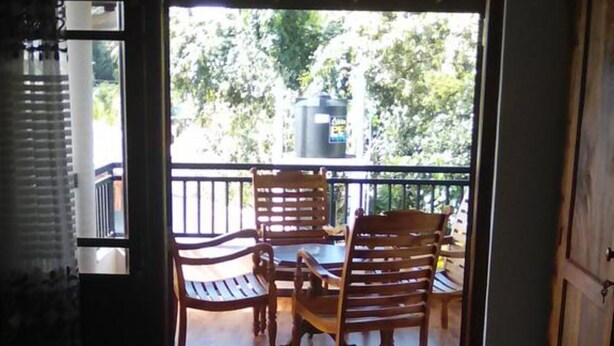 Una habitación con una cama, una mesa de madera con sillas, y una puerta abierta que da a un patio exterior con mesa y sillas.