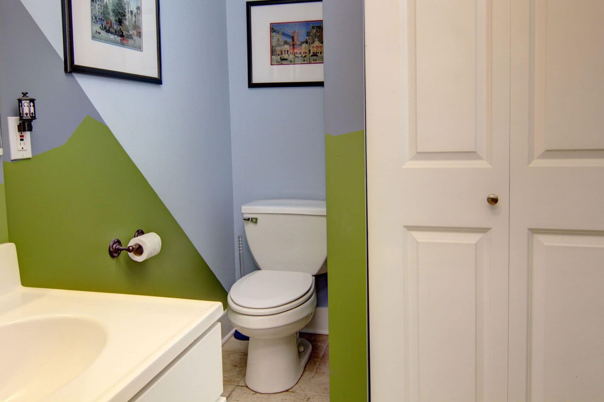 A bathroom with a toilet, a sink, and a bathtub. There are framed pictures on the wall.