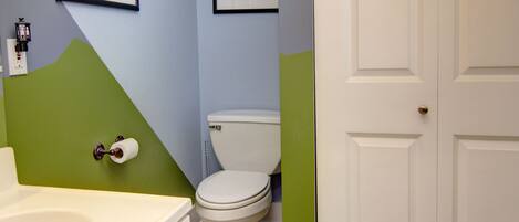 A bathroom with a toilet, a sink, and a bathtub. There are framed pictures on the wall.