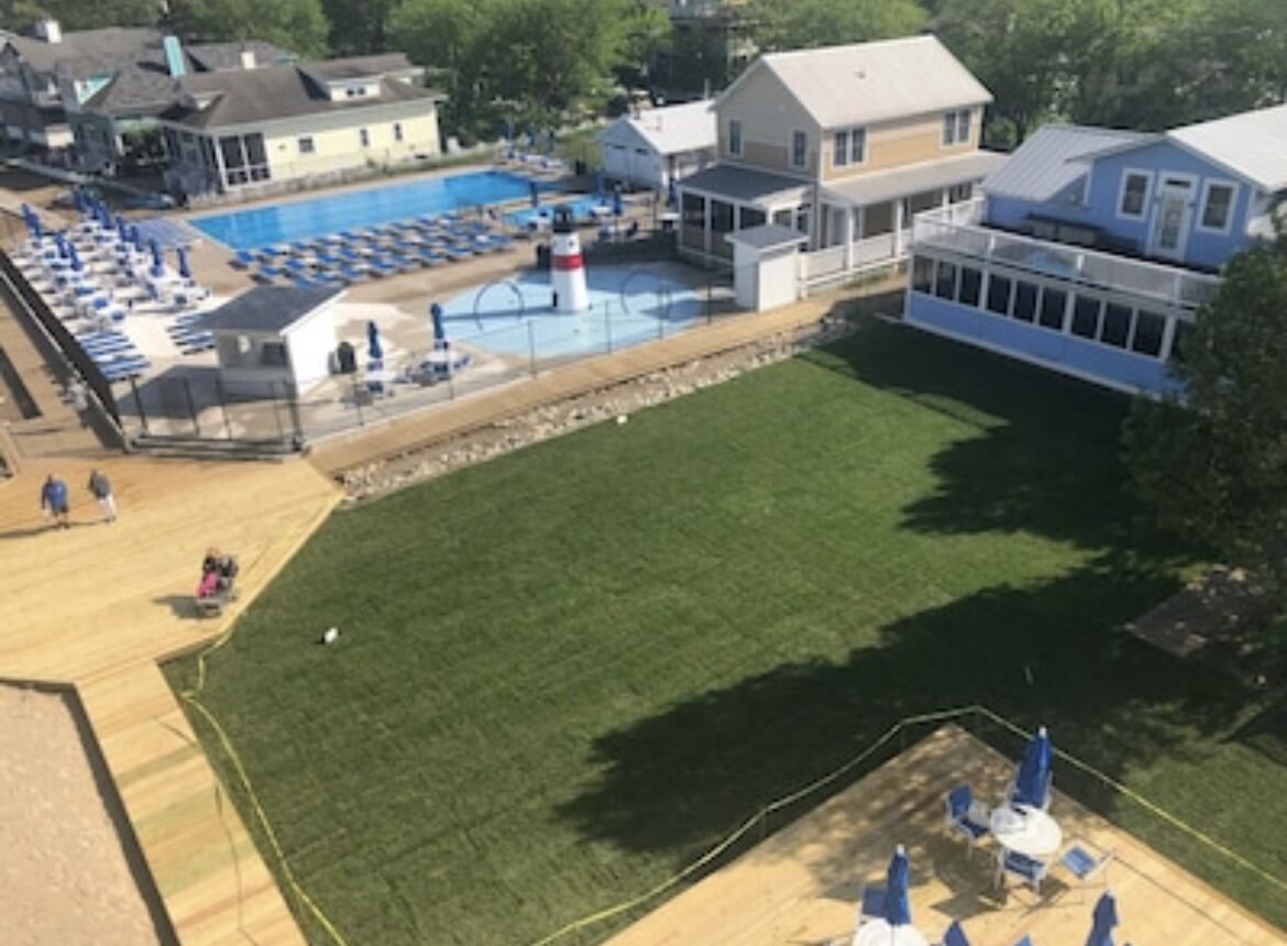 A swimming pool area with lounge chairs and a lawn.