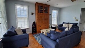 A living room with two blue sofas, a wooden cabinet, and a coffee table.