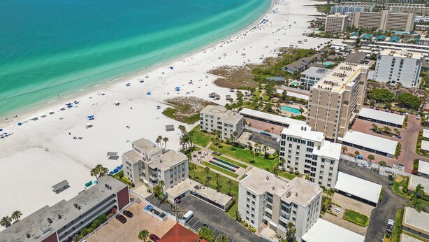 A coastal hotel with a beach view, multiple buildings, and a parking area.