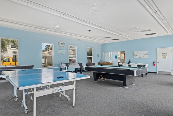 Une salle de billard équipée de deux tables de billard, d’une horloge et d’un panneau indiquant qu’il s’agit d’une zone à accès restreint.