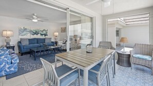 A spacious living area with a blue sofa, a wooden table, and wicker chairs.