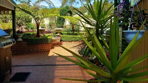 A patio area with a barbecue grill, potted plants, and a brick pathway. - Best views of Jervis Bay, A/C,heating, free Internet & beautiful large apartment (Vincentia)