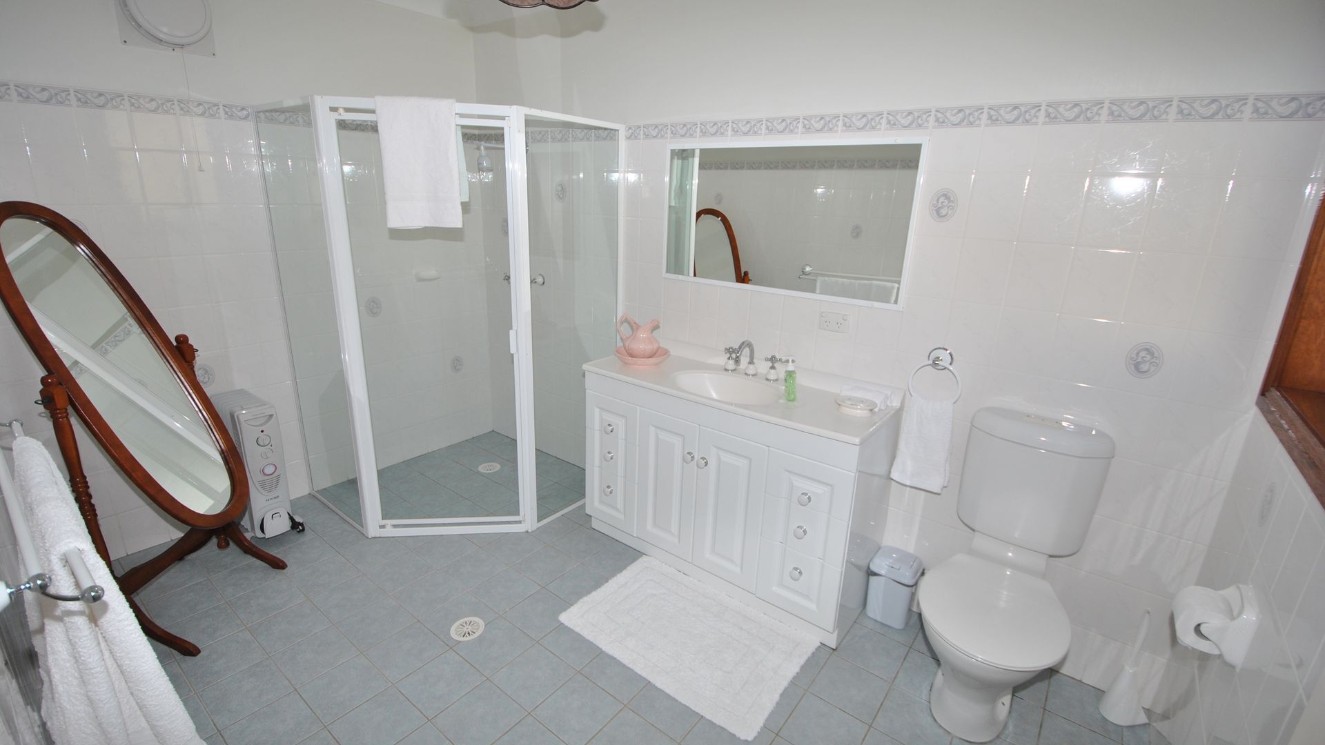 A bathroom with a shower, toilet, sink, and a mirror.