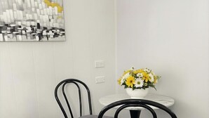 Ein Essbereich mit zwei Stühlen, einem kleinen runden Tisch und einem Blumenstrauß.