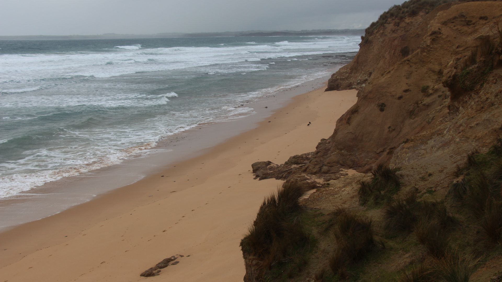 Una playa con arena y un acantilado rocoso.