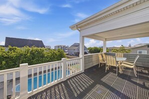A covered outdoor deck with a pool, outdoor furniture, and a view of neighboring houses.