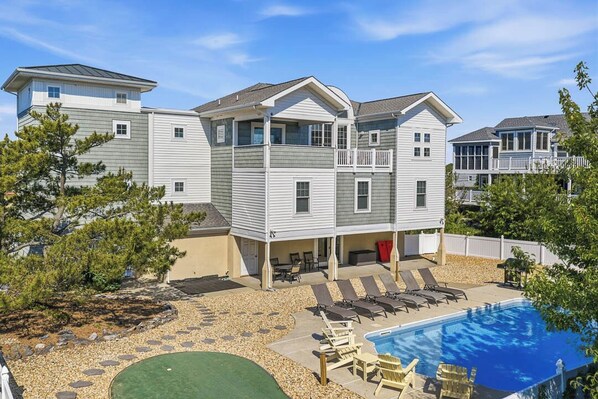 A multi-story residential building with a swimming pool, outdoor seating, and a covered patio area.