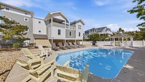Un entorno residencial con piscina, sillas de descanso y un pabellón.