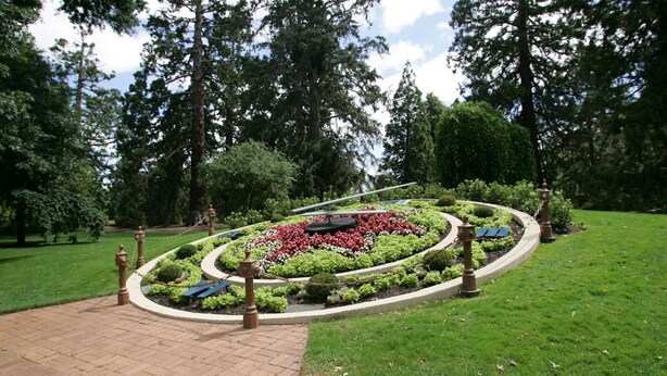 Un jardin aménagé avec un parterre de fleurs circulaire, un chemin pavé et un banc.