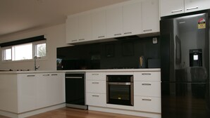 Une cuisine moderne avec des meubles blancs, un réfrigérateur noir, un four et un lave-vaisselle.