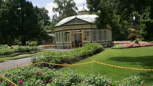 Une véranda dotée d’un toit en verre, entourée de jardins bien entretenus et agrémentée de diverses plantes à fleurs.