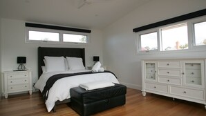 Une chambre à coucher avec un lit, une table de chevet, une commode et une fenêtre.