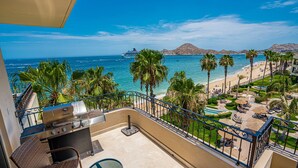 A balcony with a grill, a view of the beach, palm trees, and a cruise ship in the distance. - Spectacular OCEANFRONT - 2 Bedrooms, 4th Floor, Medano Beach & Lands End Views! (Cabo San Lucas)