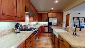 A kitchen with wooden cabinets, a stainless steel refrigerator, a microwave, and a gas stove.