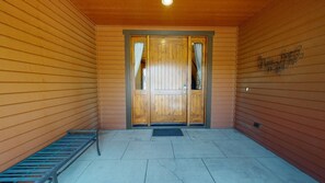 A wooden building entrance with a double door, a bench, and a metal grate. - Snowcreek Resort Vacation Rental 1302 (Mammoth Lakes)