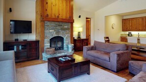 A living room with a stone fireplace, a television, a sofa, and a coffee table.
