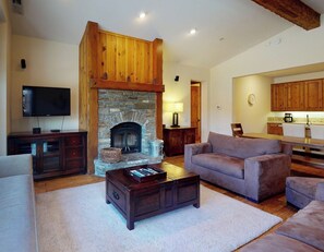 A living room with a stone fireplace, a television, a sofa, and a coffee table. - Snowcreek Resort Vacation Rental 1302 (Mammoth Lakes)