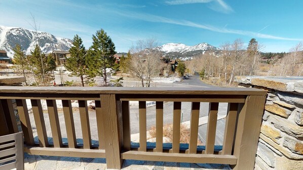 A wooden bench overlooking a road with a view of snow-capped mountains and trees.